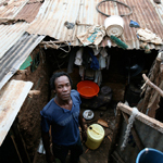 Kibera slum hphoto of man stand in a metal roofed small home