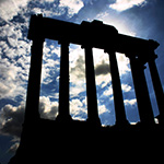 ancient roman columns silloetted against a blue sky