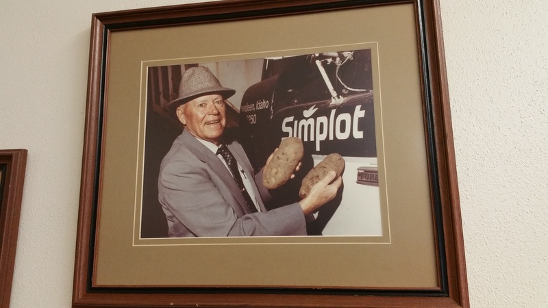 J.R. "Jack" Simplot holding potatoes near Simplot company logo