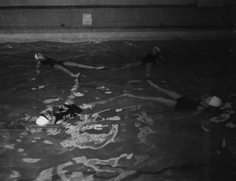 women floating in pool and linking feet