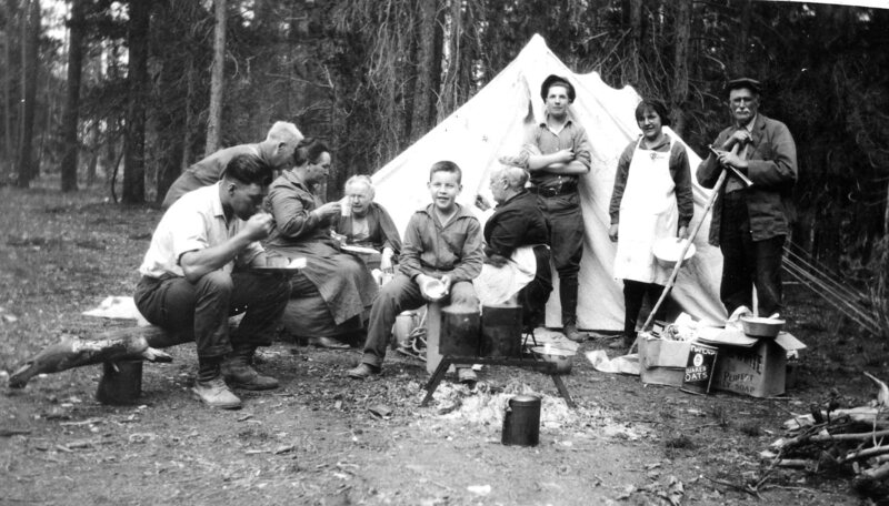 Unidentified family eating around campfire. Wall tent.