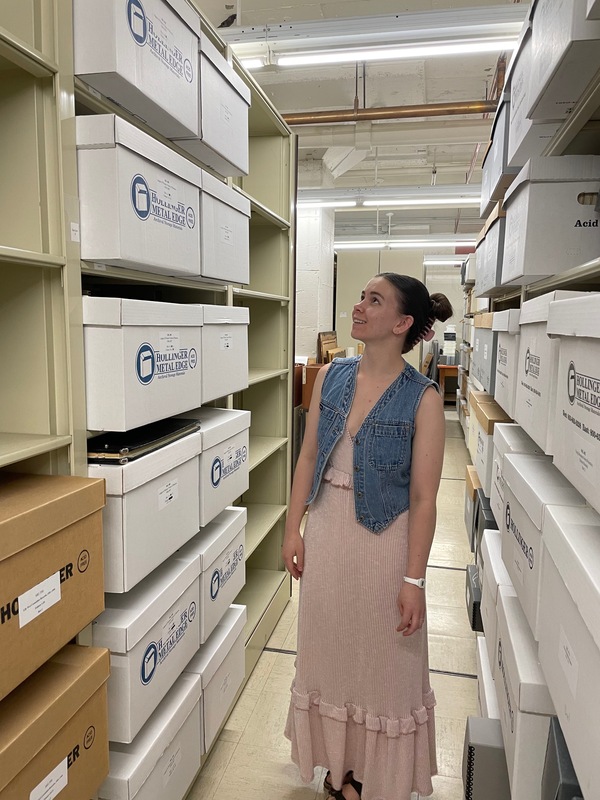 Erin Geslani standing next to a collection of boxes that she processed