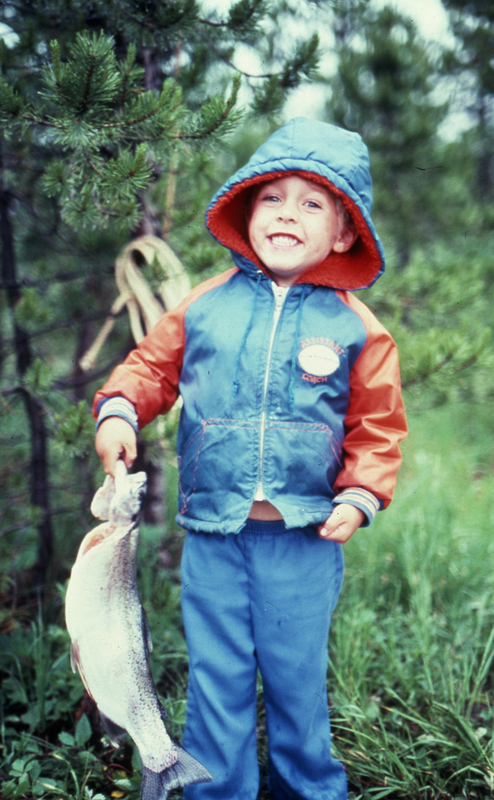 Child in the forest holding a fish.