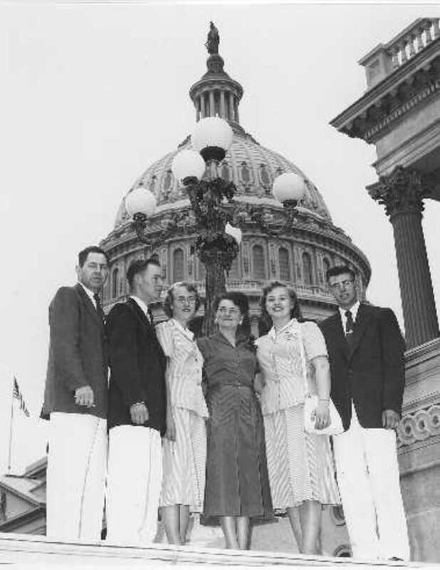 Idaho 4-H delegates standing with Idaho Congresswoman Gracie Pfost, fourth from left? in front of the Capitol. D. E. Warren, far left